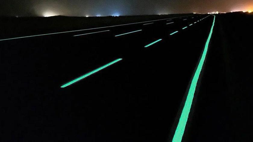 A road curve outlined with glowing green markings at night