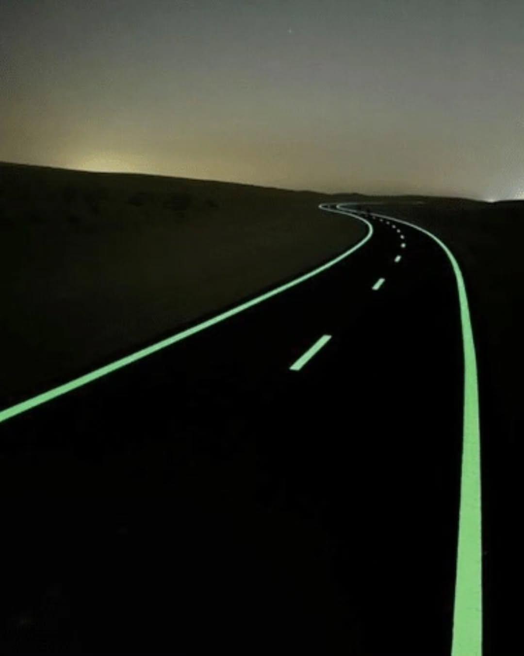 A dark road with bright glowing center and edge lines